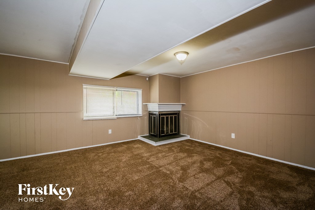A room with a carpeted floor and a window with blinds.