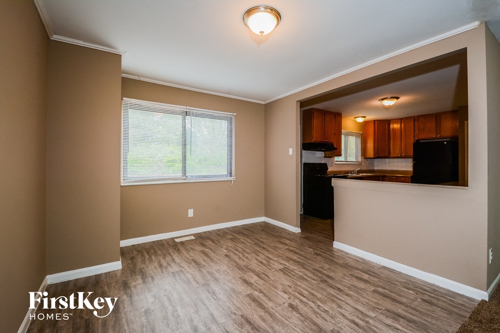 A room with a wooden floor and a window with blinds.
