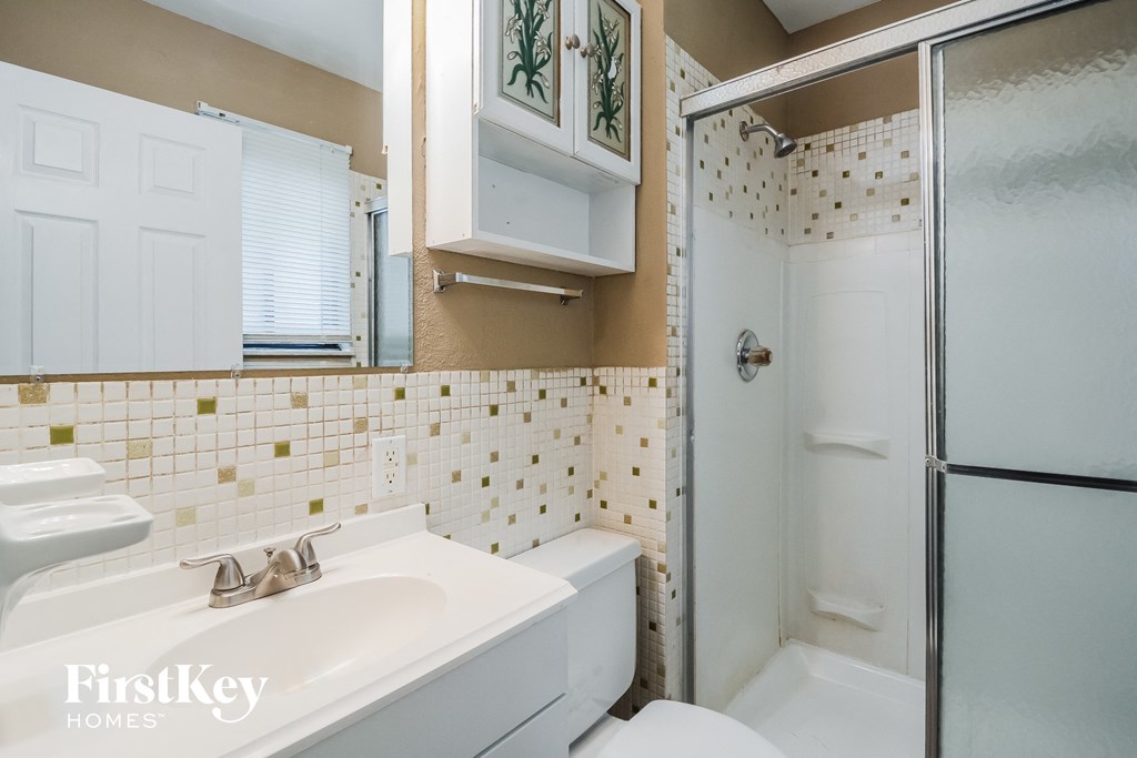 A bathroom with a white sink and a shower with a glass door.