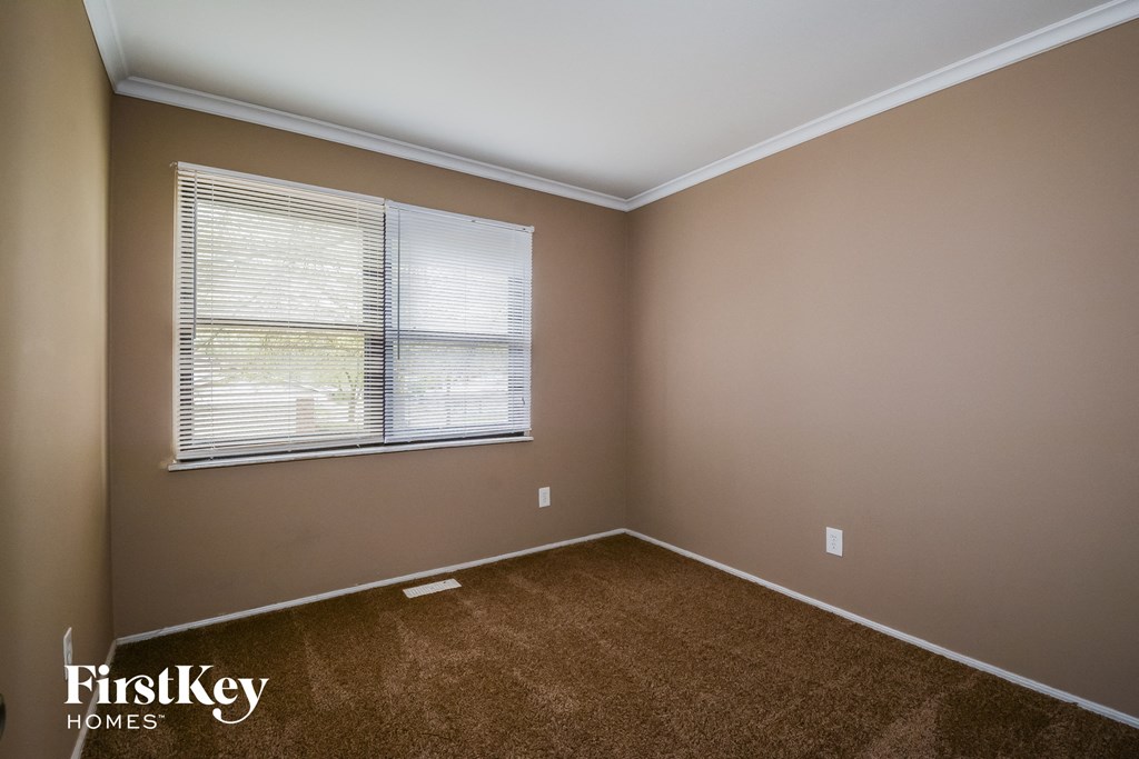 A room with a window and a carpeted floor.