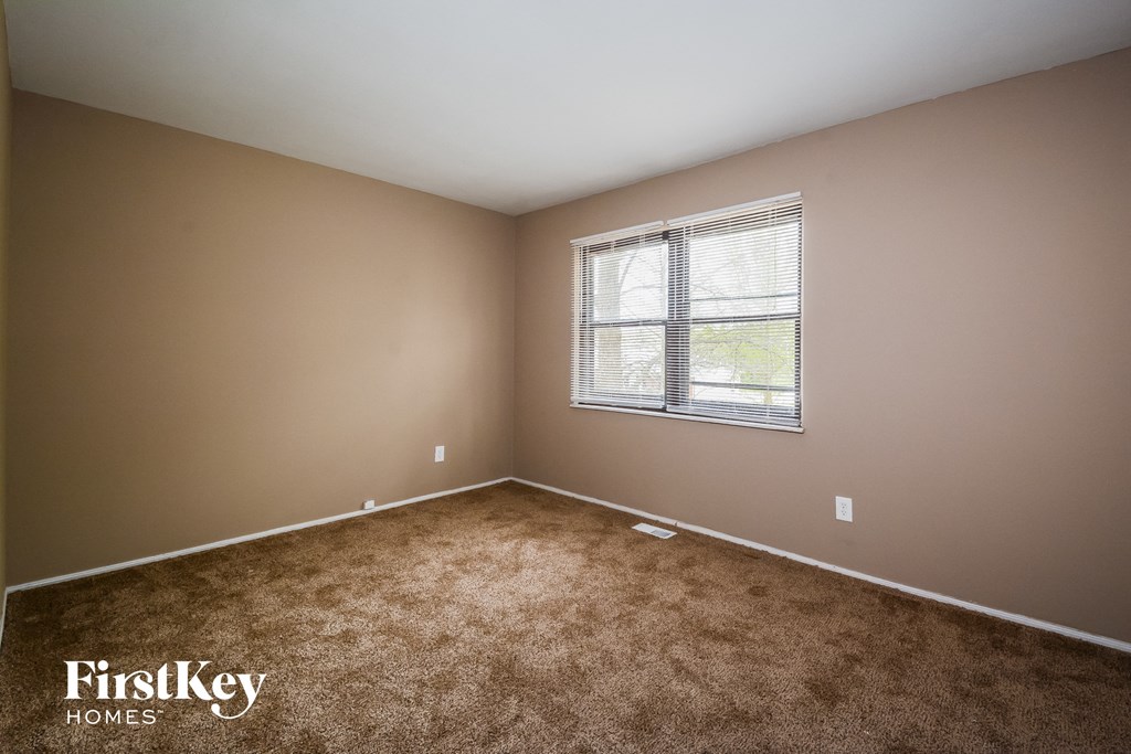 A room with a window and carpeted floor.