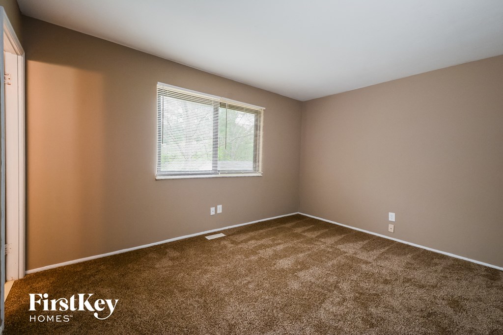 A room with a window and a carpeted floor.