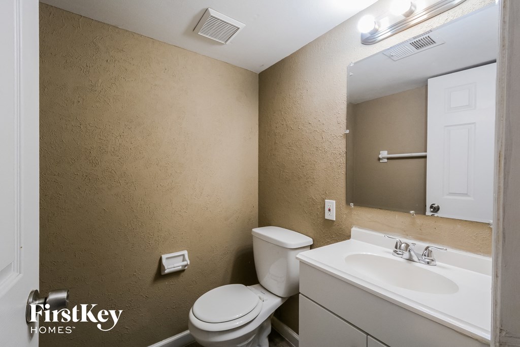 A bathroom with a toilet, sink, and mirror.