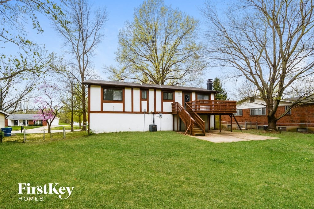 A house with a white and brown exterior is surrounded by a grassy yard.