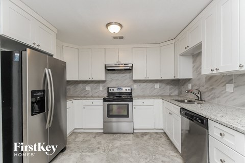 A kitchen with a stainless steel refrigerator and white cabinets.