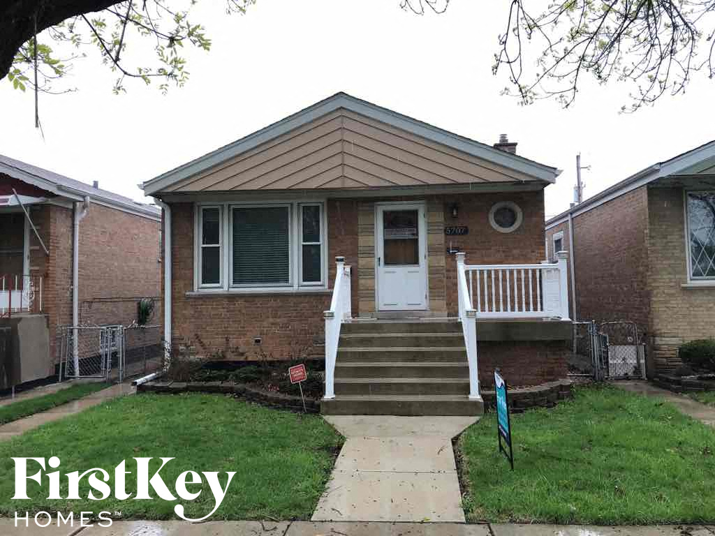 a small brick house with a porch and stairs