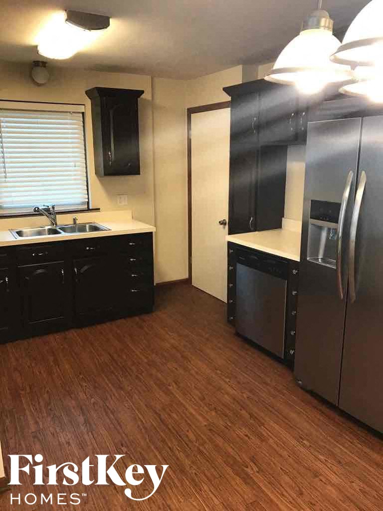 a kitchen with black cabinets and a sink and a refrigerator