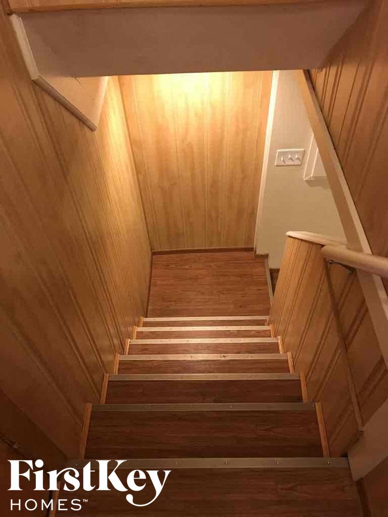 a wooden staircase with wooden floors and a light coming down the stairs