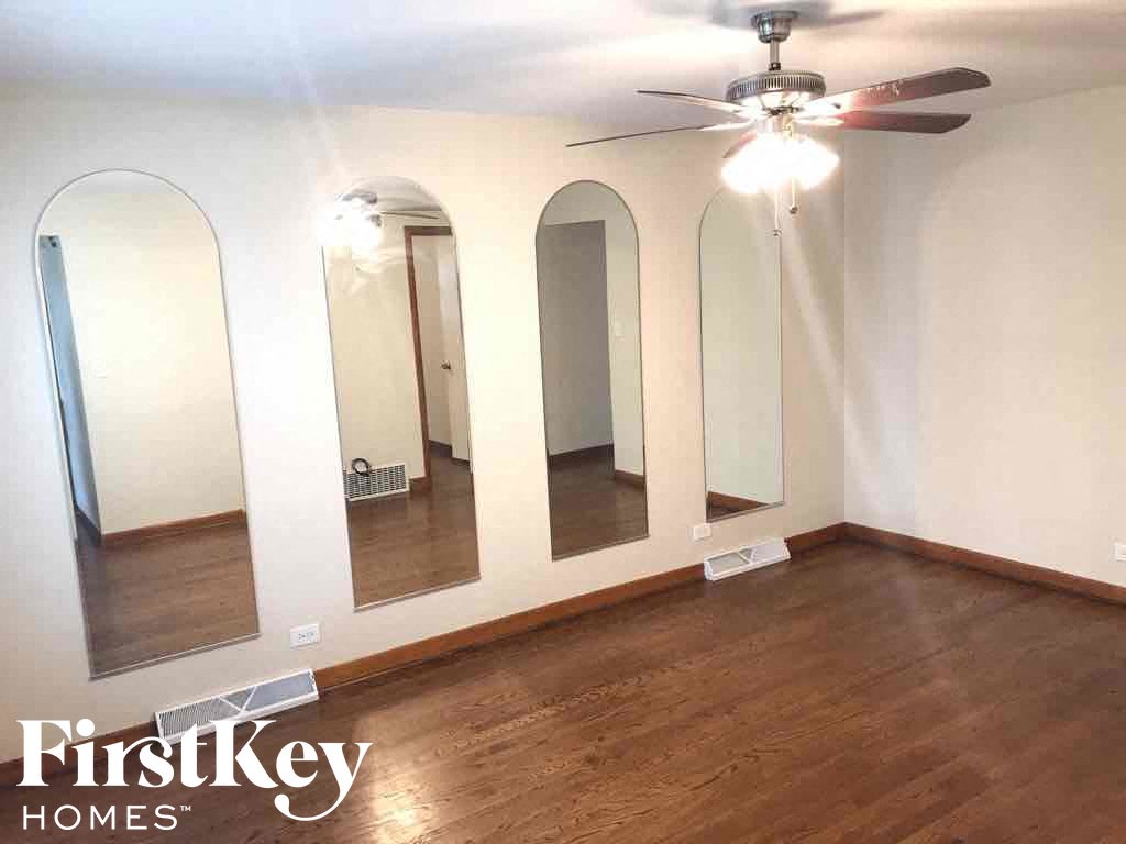 an empty room with three mirrors on the wall and a ceiling fan