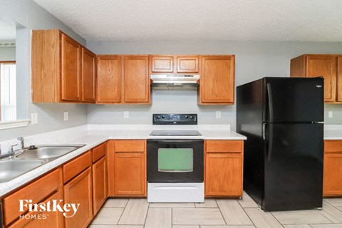 a kitchen with wooden cabinets and a black refrigerator