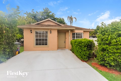 a beige home with a driveway and a palm tree