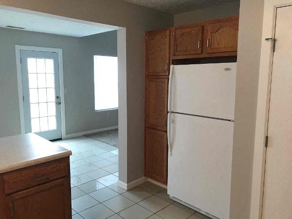 A white refrigerator in a kitchen with wooden cabinets.
