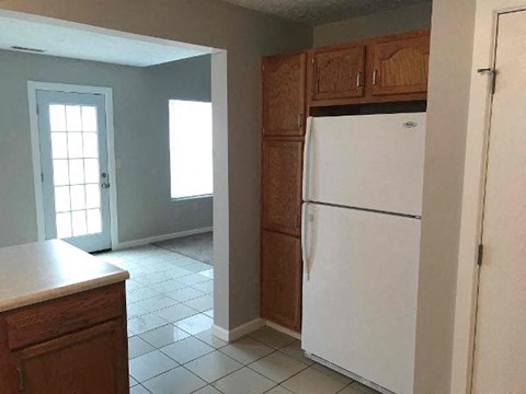 A white refrigerator in a kitchen with wooden cabinets.