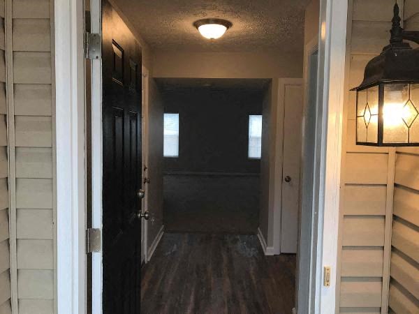 A hallway with a light on the ceiling and a door on the left.