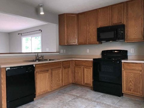 A kitchen with wooden cabinets and black appliances.