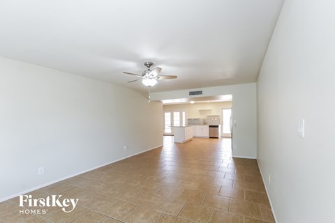 a spacious living room with white walls and a ceiling fan
