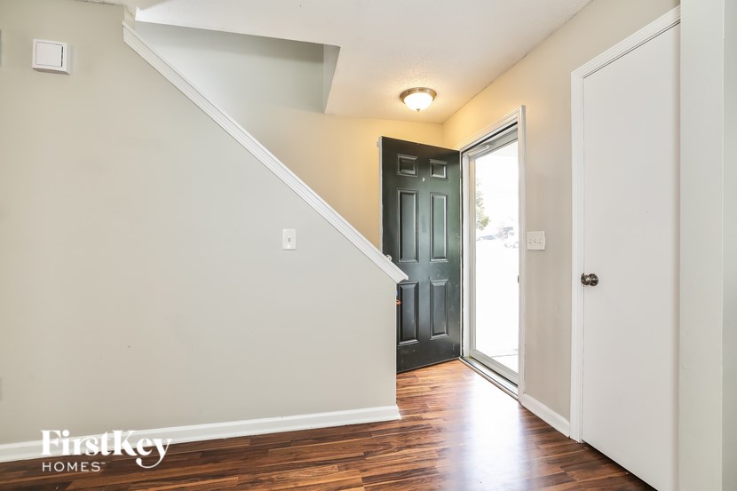 A staircase with a white railing and a black door at the top.