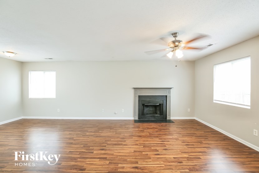 A spacious room with a fireplace and wooden floors.