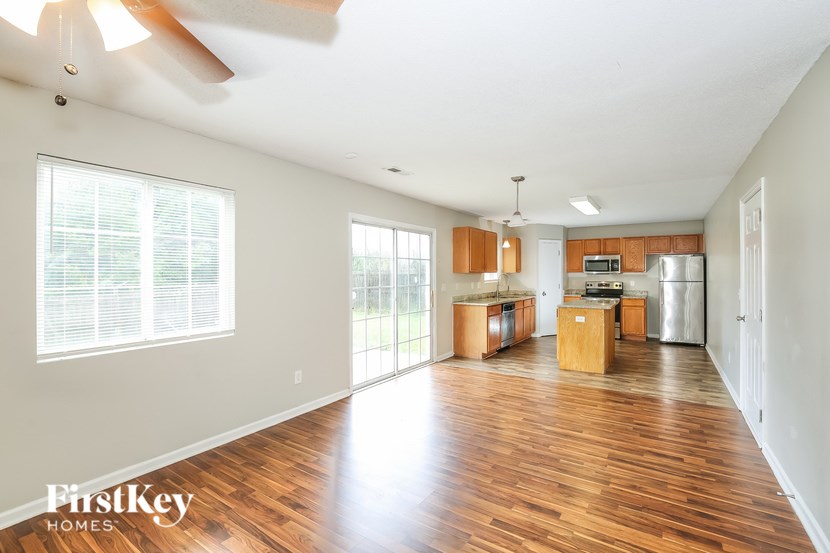 A spacious kitchen and living room with wood floors and a ceiling fan.