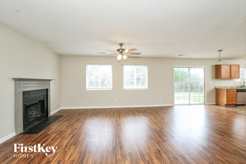 A spacious living room with wood flooring and a fireplace.