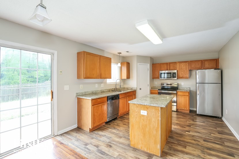A kitchen with wooden cabinets and a marble island.