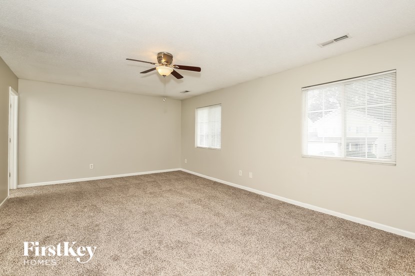 A spacious room with a ceiling fan and carpeted floor.