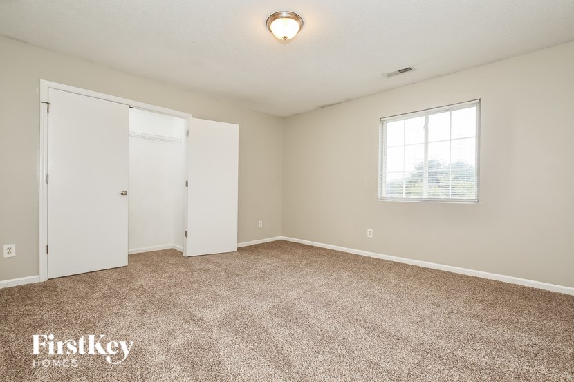 A room with a carpeted floor, a window, and a door.