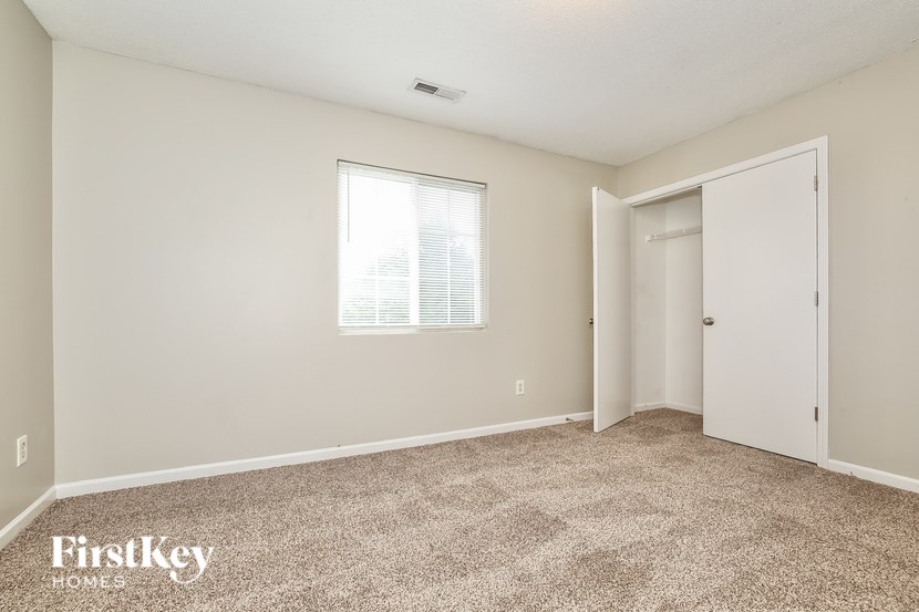 A room with a carpeted floor and a window with blinds.