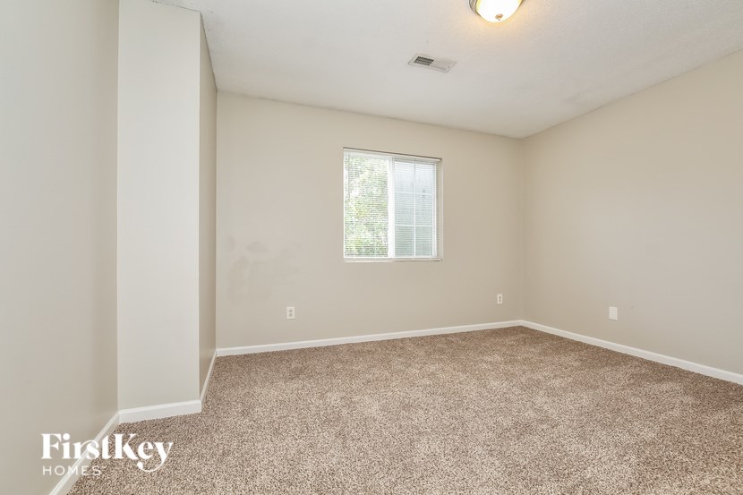A room with a carpeted floor and a window.