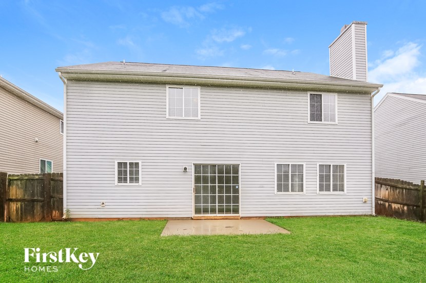 A house with a grey siding and a white door is for sale.