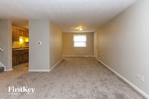 A spacious room with a carpeted floor and a window.