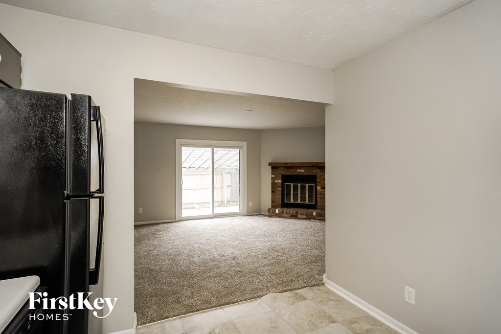 an empty living room with a refrigerator and a fireplace