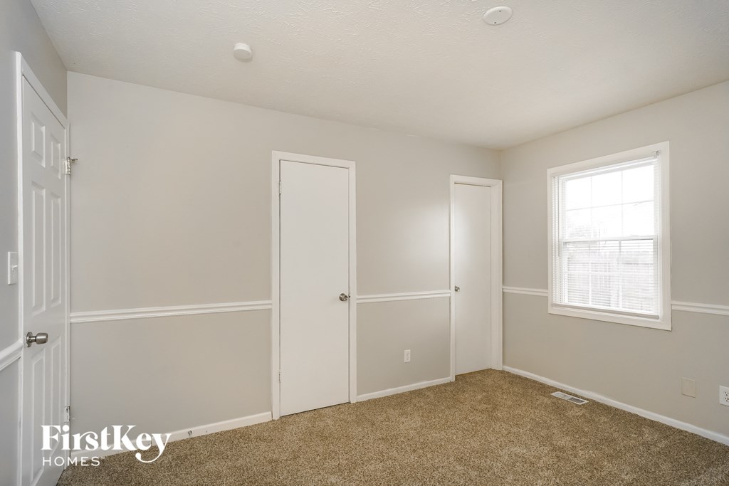 a bedroom with white walls and white doors and a window