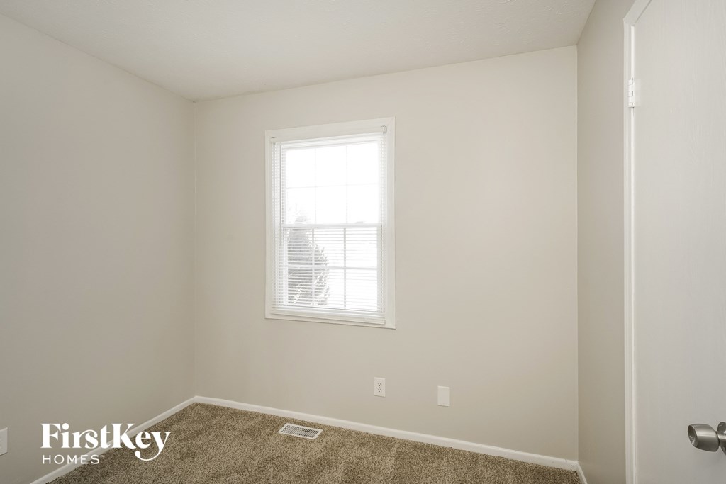 a bedroom with a window and a carpeted floor