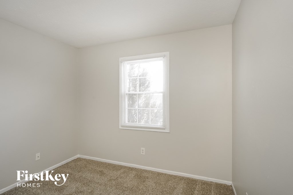a bedroom with a window and a carpeted floor