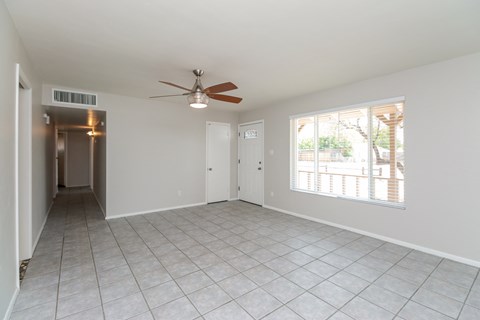 A spacious room with a ceiling fan and tiled flooring.
