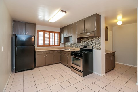 A kitchen with black appliances and brown cabinets.