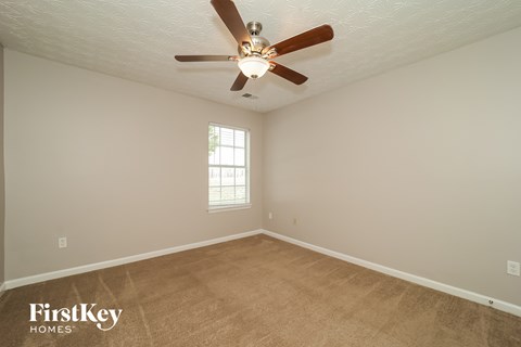 the spacious living room with ceiling fan and carpet