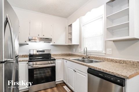 a kitchen with white cabinets and granite counter tops and stainless steel appliances