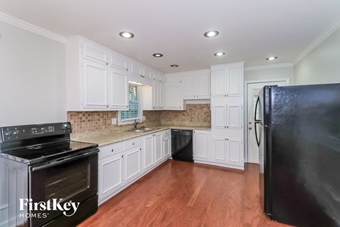 A kitchen with white cabinets and a black refrigerator.