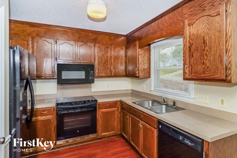 A kitchen with wooden cabinets and a black dishwasher.