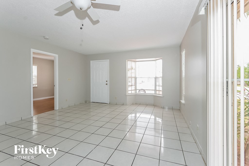 an empty living room with a white tile floor and a ceiling fan