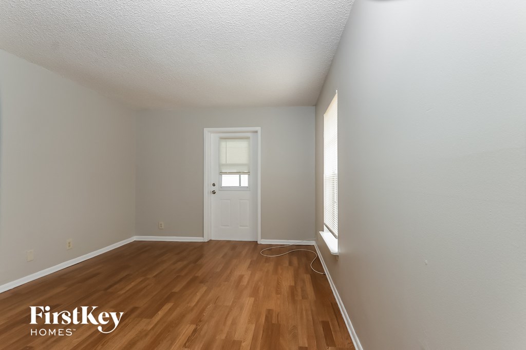 the living room of a house with wooden floors and a white door