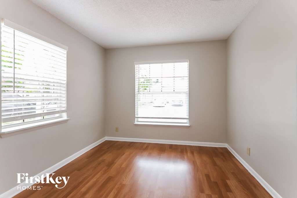an empty living room with wood floors and two windows