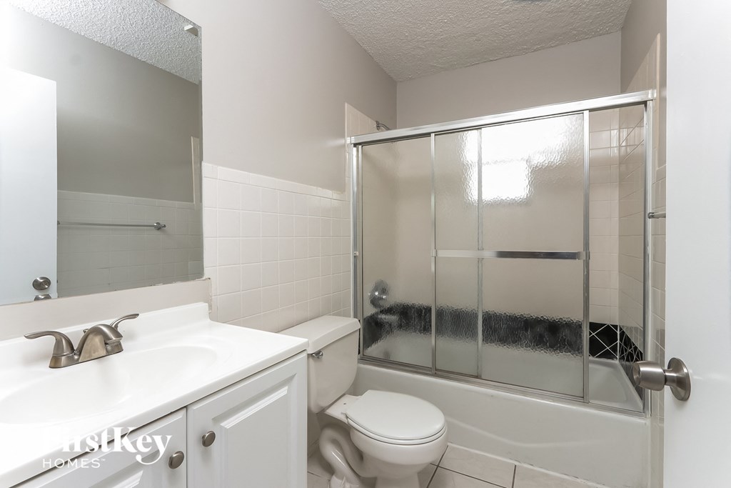 a white bathroom with a shower toilet and sink