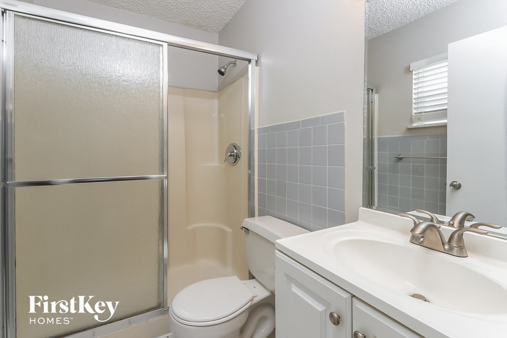 a white bathroom with a shower toilet and sink