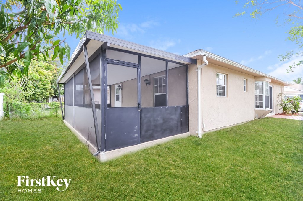 a home with a screened in porch and a grass yard