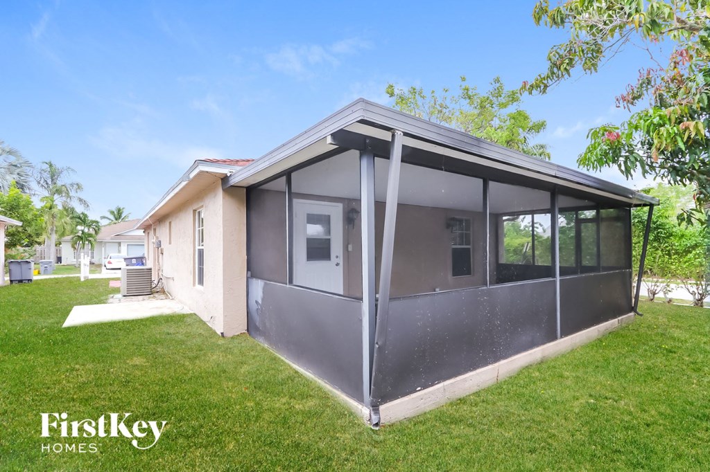 a small screened porch in a backyard with a house