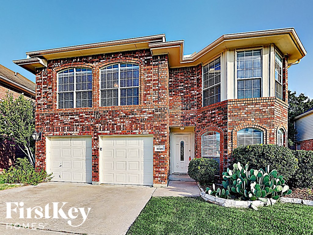 a brick house with two white garage doors