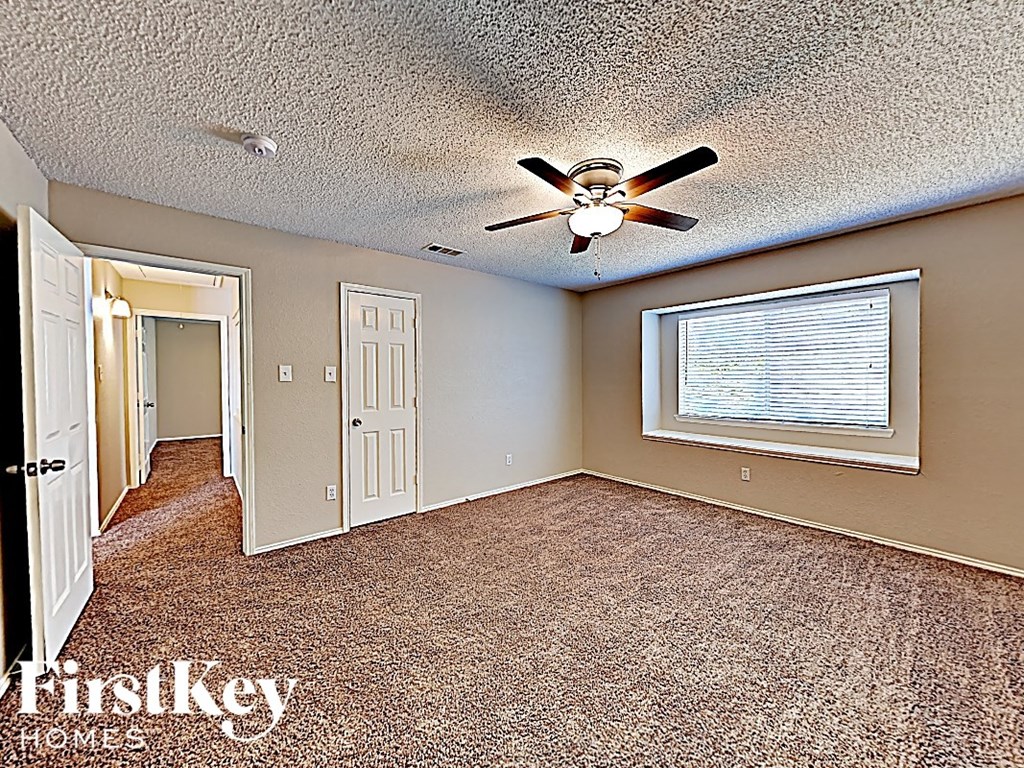 an empty living room with a ceiling fan and a window